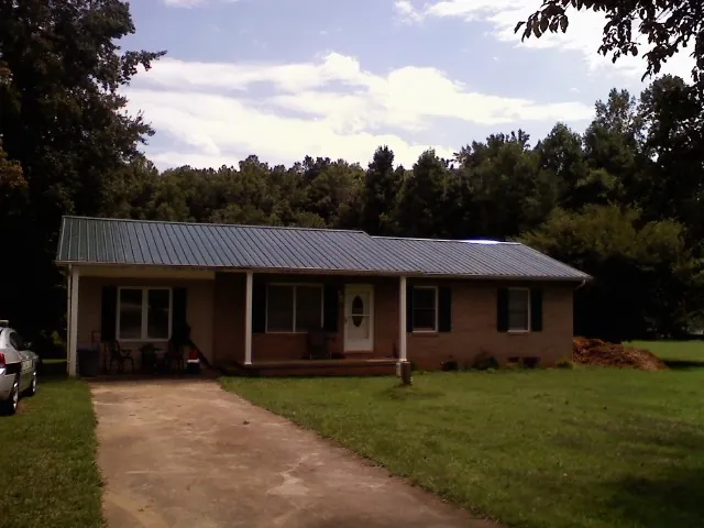 Dark green metal roof on a brick ranch with a covered porch in Windham