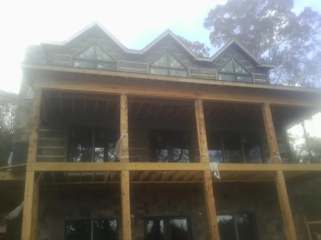Dormers and porch framing on a large log home under construction — Roof Coating work by our crew in Windham